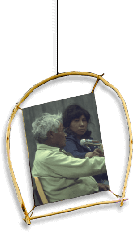 An old man sitting speaking into a microphone