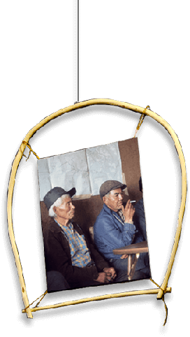 Two old men sitting at a table. One is smoking.